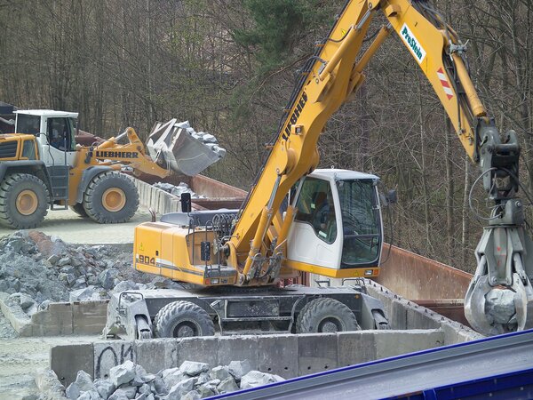 Radlader und Bagger verladen Schotter in Eisenbahnwaggons