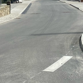 Neu asphaltierte Straße mit Bordstein und Gehweg