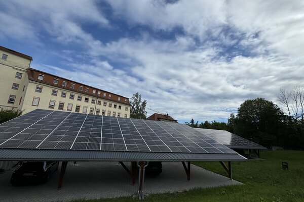Photovoltaikanlage auf einem Carport vor historischem Gebäudekomplex