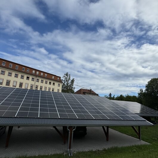 Photovoltaikanlage auf einem Carport vor historischem Gebäudekomplex