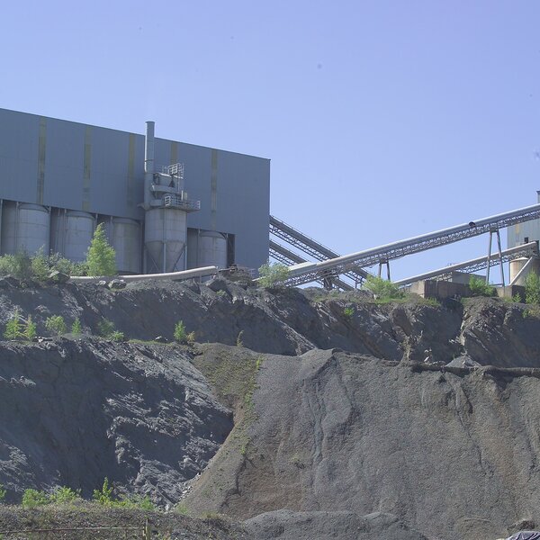 Aufbereitungsanlage mit Silos und Förderband auf einer Felskante